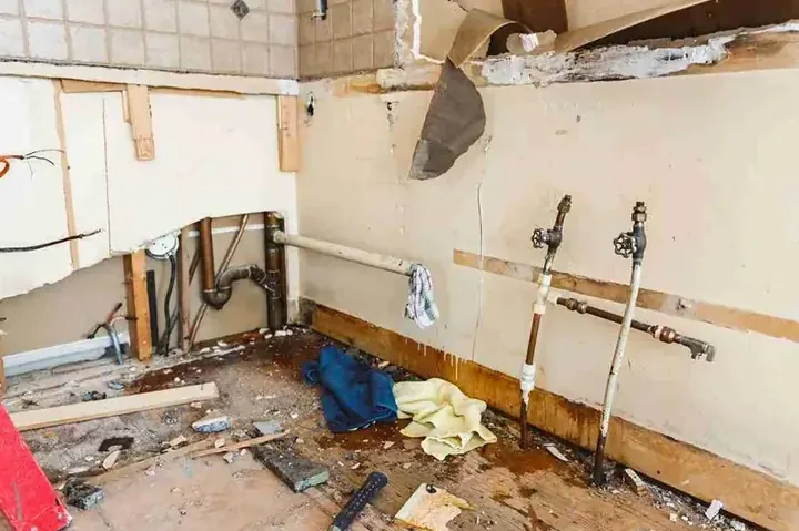 Kitchen wall opened to supply valves, cabinets removed, debris below